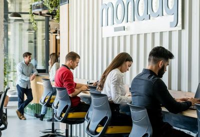 Long communal desk with high-back chairs against a corrugated metal wall.