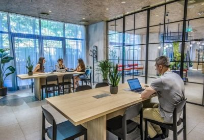 Meeting area with wooden desks and large glass windows overlooking greenery.