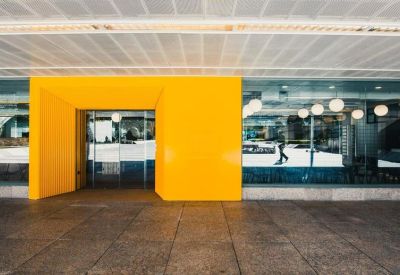 Main entrance featuring a bold, minimalist yellow facade and glass doors.