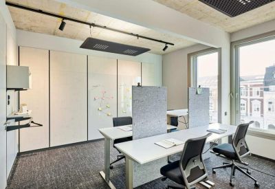 Bright workspace with white desks, grey partitions, and large windows.