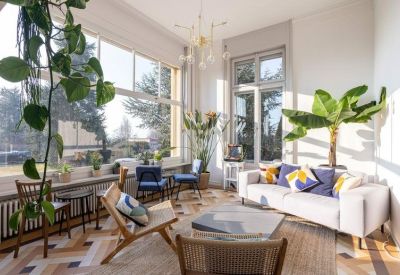 Sun-drenched lounge area with a white sofa, potted plants, and eclectic furniture.