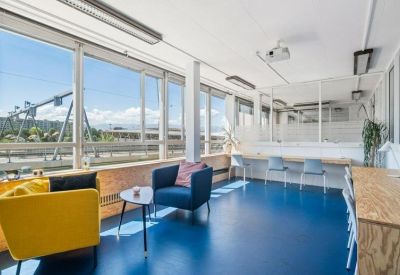 Luminous workspace with blue flooring, comfortable seating, and large windows with mountain views.