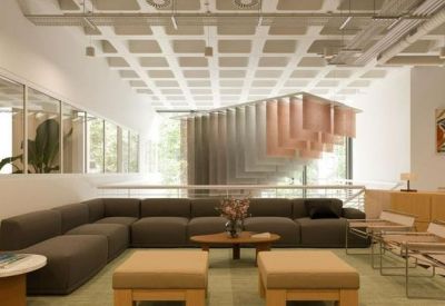 Spacious communal lounge with a large grey sectional sofa and unique geometric ceiling design.