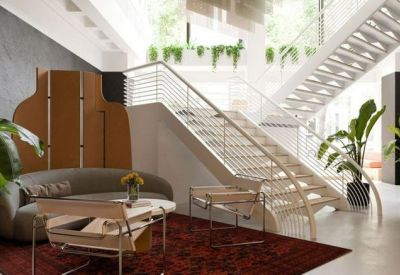 Modern breakout area featuring a white staircase, indoor plants, and a plush curved sofa.