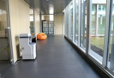 Modern office corridor with floor-to-ceiling windows and a white printer unit.