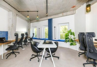 Spacious coworking area with ergonomic chairs, blue accents, and hanging pendant lights.