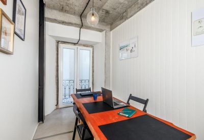 Bright office space featuring an orange wooden desk and industrial concrete ceiling.