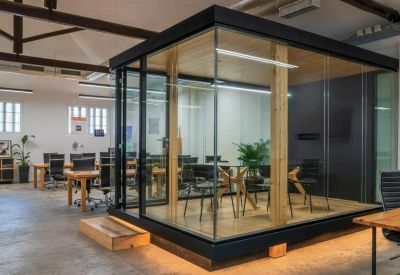 Sleek glass-walled meeting pod with wooden accents and indoor greenery.