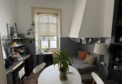 Communal dining and lounge area with grey walls and wooden floors.