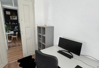 Single workstation with white desk and view into a kitchen area.