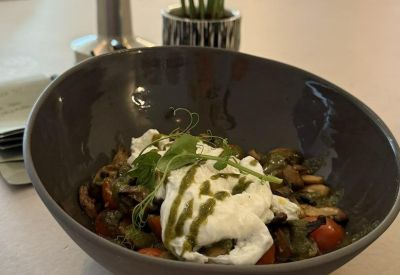 A colorful vegetarian bowl topped with poached eggs and pesto.