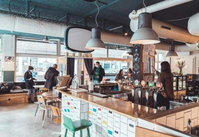 Spacious communal cafe area with a tiled bar and industrial lighting.