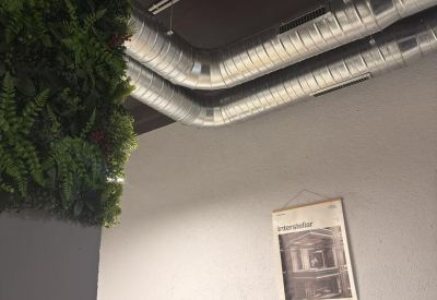 Industrial style ceiling with exposed silver ventilation ducts above a brick accent wall.