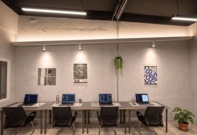 Modern coworking office space with four laptop stations and wall art.