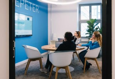 Bright meeting room with circular lighting, glass walls, and a round wooden table.