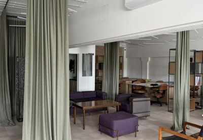 Cozy breakout space with a purple ottoman and soft green curtains used as room dividers.