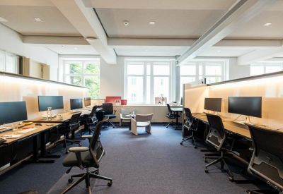 Bright open-plan office space with multiple monitor setups and ergonomic chairs.