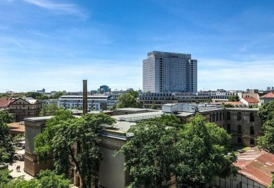 Elevated exterior view showing the building surrounded by green trees under a clear blue sky.