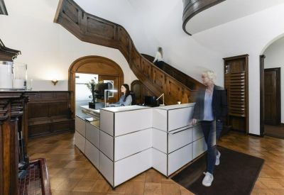 Classic reception area with an ornate wooden staircase and modern modular desk.