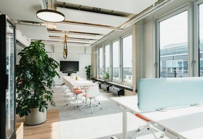 Bright conference room featuring a long white table, green potted plants, and large windows with city views.