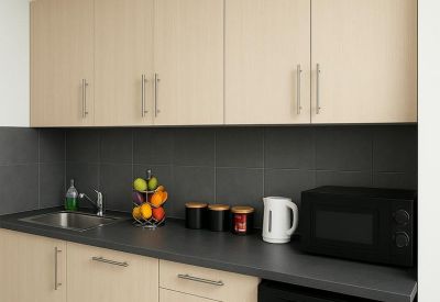 Modern kitchenette with light wood cabinetry and integrated appliances.