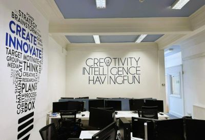 Creative workspace featuring motivational wall graphics and several computer monitors.