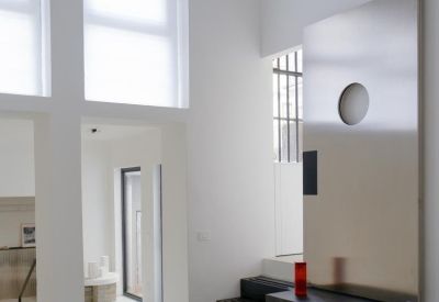 Minimalist reception area featuring a large metal door and black geometric stairs.