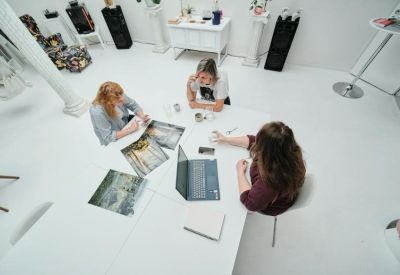 Aerial view of a team collaborating at a white table with architectural drawings and a laptop.