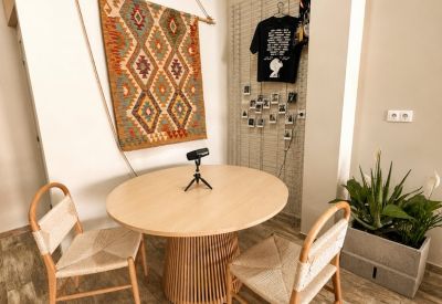 Meeting nook with a round light wood table, woven chairs, and a decorative wall hanging.