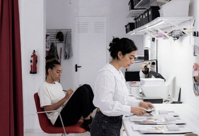 Creative studio with people working at a long table near industrial storage shelves.