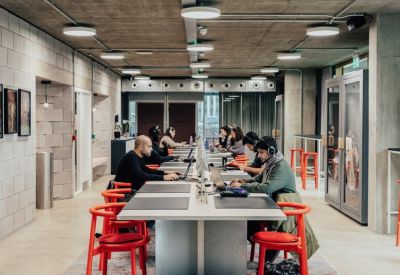 Spacious open-plan coworking area at Design District, 13 Soames Walk with long tables and red stools.