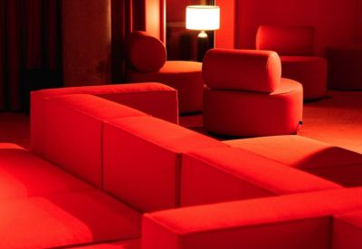 Striking monochromatic red lounge area with modular seating and a glowing table lamp.