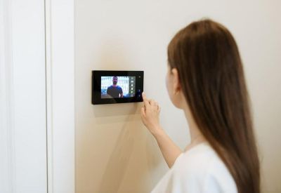 Woman using a wall-mounted digital touch screen panel for office security or controls.