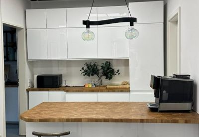 Modern communal kitchen area with wood countertops, white cabinetry, and breakfast bar.