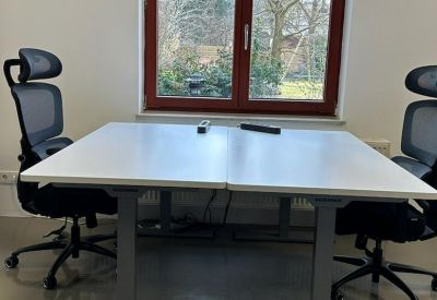 Dual workstation setup featuring sit-stand desks in front of a large window.