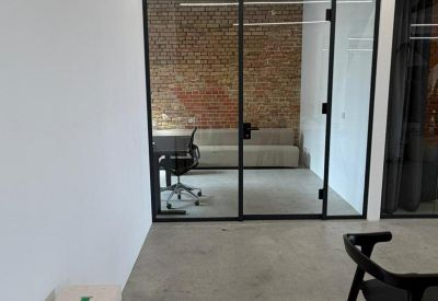 Glass-walled private meeting room or office with a brick feature wall and sofa.