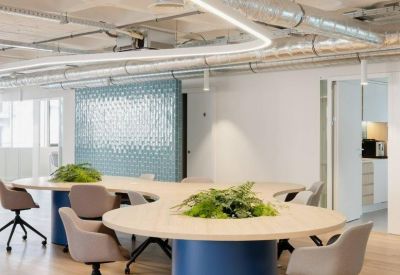 Curved coworking table with blue bases and integrated planters under modern lighting.