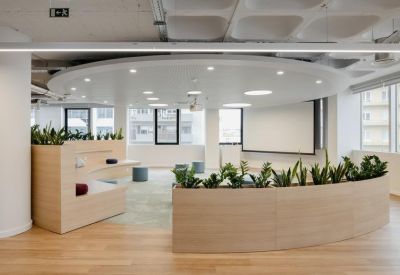 Circular auditorium seating area with wooden tiers, integrated planters, and a projector screen.