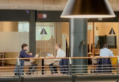 Elevated view of professionals working at a long wooden table under large cone-shaped pendant lights.