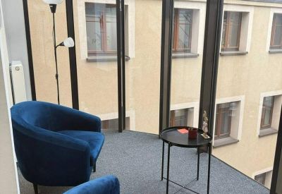 Bright glass-walled breakout area with navy blue velvet armchairs and city views.