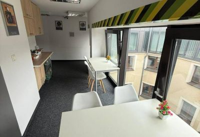 Modern office kitchen area with white tables and colorful striped wall accents.