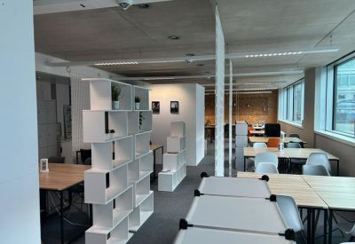 Bright open-plan workspace with white modular shelving units and wooden desks.