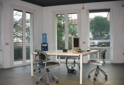 Bright workspace at 18, Via Pietro Giordani, featuring a large white table and tall windows.
