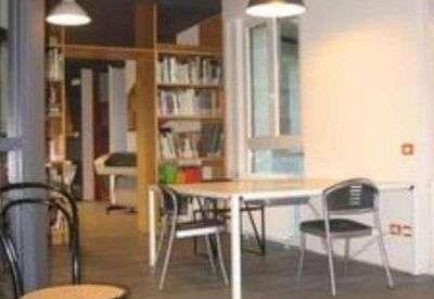 Communal dining area with pendant lighting and a large bookshelf.