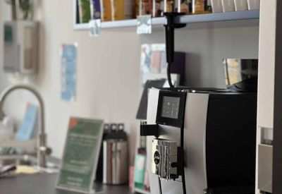 Sleek office kitchen area with a high-end coffee machine and snacks on a blue shelving unit.