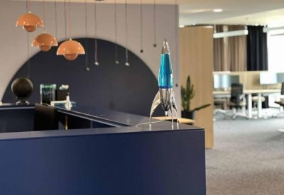 Reception desk featuring a creative rocket-shaped lava lamp and stylish orange pendant lights.