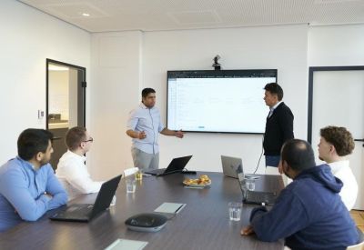 Team meeting in a conference room featuring a large wall-mounted presentation screen.