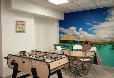 Breakout room featuring a foosball table and a cafe seating area with a tropical beach mural.