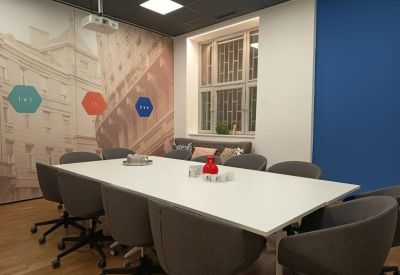 Conference room with a large white table, gray chairs, and a historical Budapest wall mural.