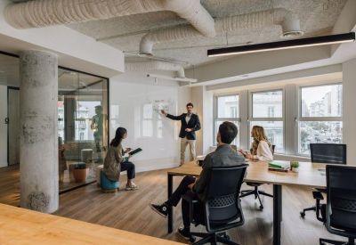 Professional meeting room with a whiteboard, large windows, and exposed ceiling ducts.